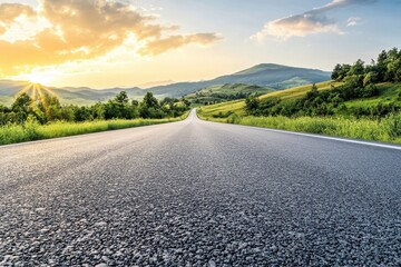 Empty asphalt road leading through green rolling hills towards a golden sunset.