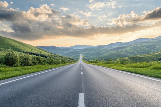 A long, straight road winding through green hills and disappearing into the horizon under a cloudy sky.