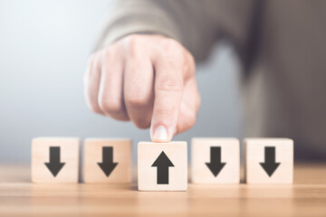 A man selecting an arrow symbol on wooden blocks, symbolizing the concept of thinking in different directions and exploring alternative perspectives in decision-making