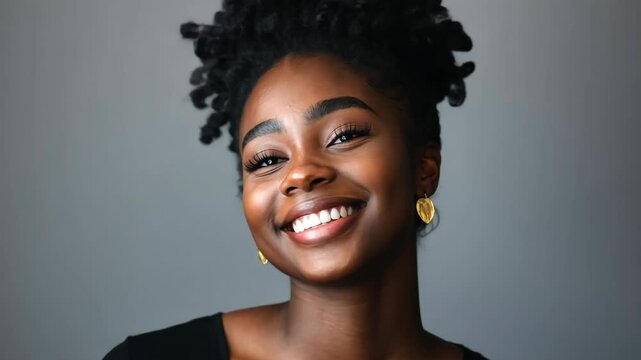 A young woman with a big smile and her hair in a bun poses for a photo