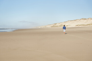 Homme seul qui marche sur une plage déserte