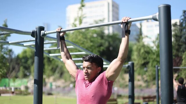 Determined athlete performing pull ups on horizontal bar