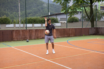 Fototapeta premium Volleyball player practicing ball control on a hard court, focusing on precision and movement during an outdoor training session. Captured in a calm, focused moment