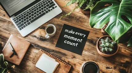 A laptop, coffee, plants, and a notepad sit on a wooden desk with a motivational quote, Make every moment count