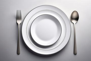 A simple white plate, fork, and spoon set against a plain gray and white background, highlighting the essence of dining and mealtime setup