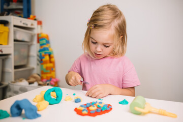 Young child engaged in creative play with colorful modeling clay at home in the afternoon