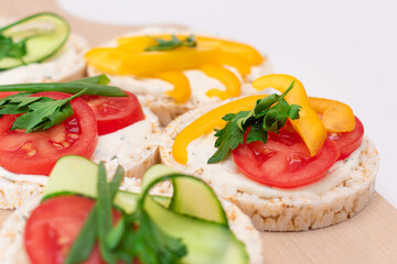 Different Vegan Rice Cake Sandwiches with Fresh Tomato, Yellow Paprika and Greens on Wooden Cutting Board. Vegetarian Diet Food. Quick and Healthy Sandwiches. Crispbread with Fresh Fillings