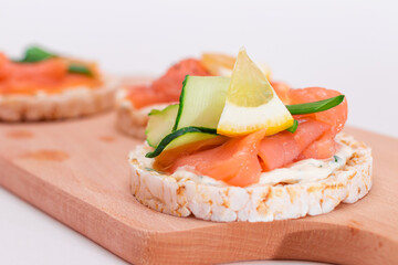 Rice Cake Sandwiches with Fresh Salmon, Cucumber, Lemon and Greens on Wooden Cutting Board. Diet Food. Quick and Healthy Sandwiches. Crispbread with Fresh Fillings. Healthy Dietary Snacks