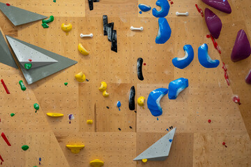 Pared con agarres de escalada artificiales en rocódromo interior.