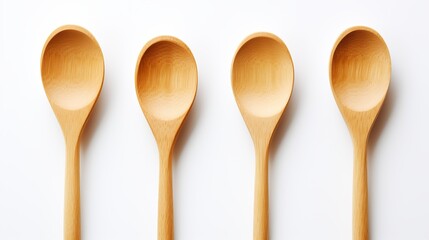 Four wooden spoons arranged neatly on a white background showcasing their natural finish and design