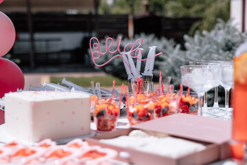 Table decoration for a bachelorette party. Pink accessories, wine and flowers. Cake with letters Bride to be