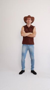 Modelo masculino vaqueiro da moda usando jeans e colete marrom e chap&eacute;u 