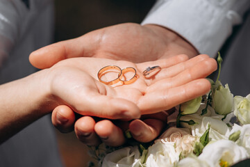 Close-up photo of the men`s holding woman hand with golden wedding ring with diamond. Wedding ring before the proposal. Luxury wedding rings