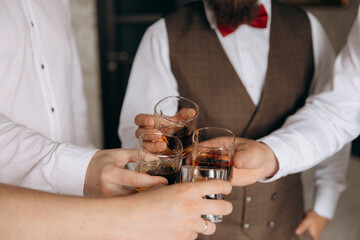 Close-up of hands with clinking whiskey glasses. Cheers mate