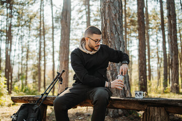 Young caucasian man drinking water taking break from hiking or trekking
