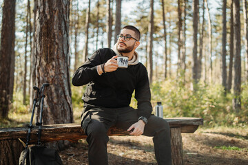 Young caucasian man drinking water taking break from hiking or trekking
