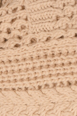 A fragment of beige knitted fabric, knitted from white sheep wool.