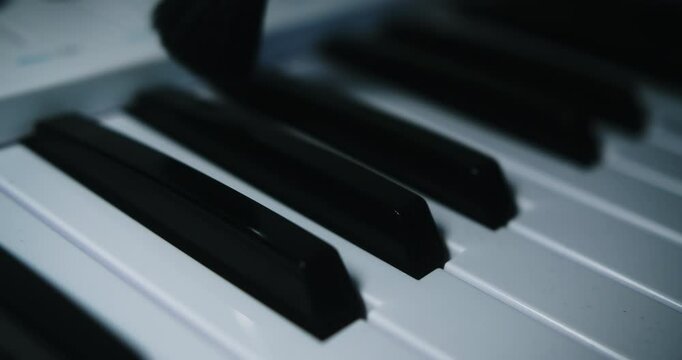 Beautiful slow motion and super close-up shot of a musician cleaning his midi controller keyboard with a brush from an instrument cleaning kit in his home studio.
