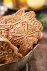 Bowl of speculaas biscuits, golden candles in the background.