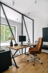 A modern home office with sleek furniture and a view of the forest during daylight hours