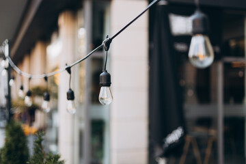 Hanging Outdoor String lights. Decorative Outdoor Street electric garland. Old light bulbs. Lamp hang in the yard. Terrace concept. Festoon string lights decoration at the party
