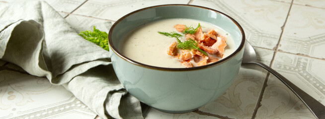 blue bowl with celery root, leek and fennel soup with salmon on light table