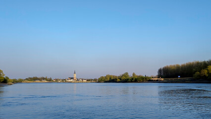 Fototapeta premium Riverside Charm in Puurs-Sint-Amands: Cultural Landmark Meets Natural Beauty