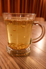 Herbal Tea with Floating Grains in Glass Mug on Wooden Table