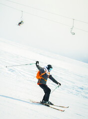 Close up dynamic sports banner of man skier on piste ski downhill fast motion in Alps. Active winter holidays, skiing downhill in overcast day. Ski rides on the track with swirls of fresh snow