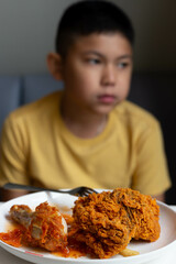 A boy with fried chicken on the table.