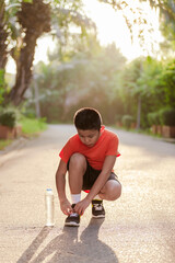 A boy ties his shoelaces in a public park..