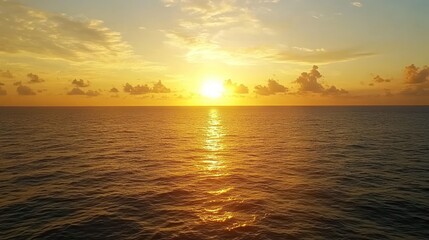 Obraz premium A stunning sunset over the ocean with a golden sky and clouds.