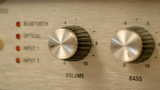 A man's finger presses the on off switch on a modern retro style amplifier (portable loudspeaker). Closeup. Macro. Shallow depth of field. Shot in motion. Follow focus