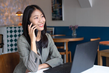 Smiling young Asian business woman executive using laptop working in office. Professional businesswoman calling with clients