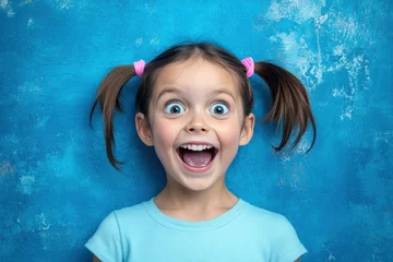 Joyful Child with Bright Expression on Blue Background © Nico