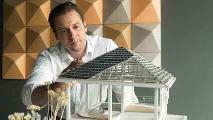 Closeup image of handsome caucasian engineer face inspects roof material while looking at building...