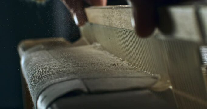 Super slow motion macro of artisan touching threads with flying dust or talc powder particles splashing around, while working with woven weaving machine to craft cloth piece in workshop at 1000 fps. 