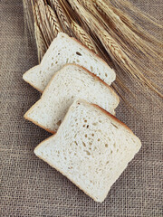 Square pieces of white toast bread and ears of dry wheat