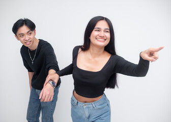 A young asian woman guiding her slightly reluctant boyfriend forward while walking, holding his hand and pointing to something interesting. Isolated on a white background.