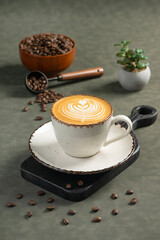 Latte with Coffee Art: A ceramic cup of creamy latte adorned with a beautiful heart shaped coffee art, placed on a rustic board. Scattered coffee beans and a scoop emphasize its rich aroma.
