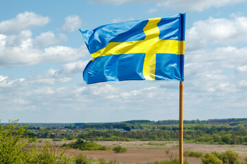The national flag of Sweden is waving in the wind in the sky with clouds. The concept of...