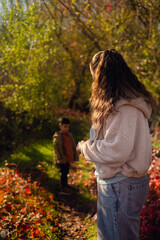 A mother and son gather mushrooms in an autumn forest, enjoying family time collecting herbs and berries—an eco-friendly hobby.