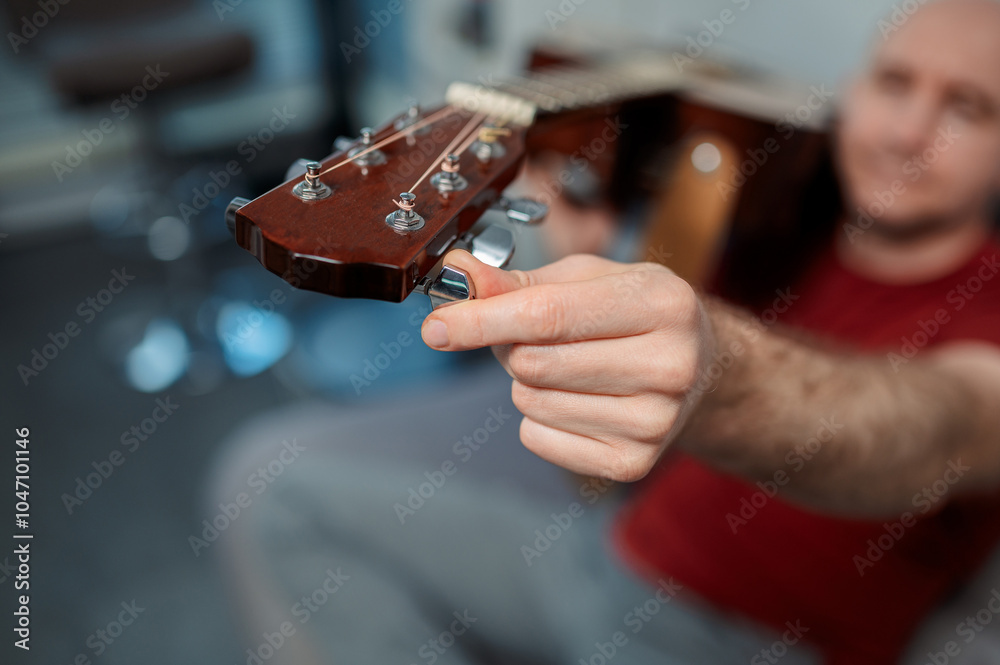 Wall mural guitarist tuning acoustic guitar and playing. close up in studio