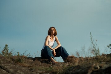 Beautiful girl with short haircut poses in nature in white T-shirt and jeans