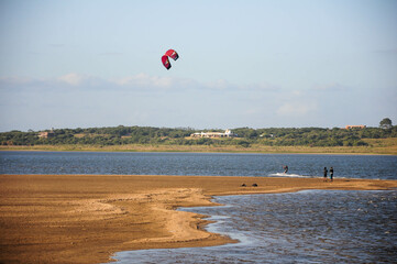 Kite surfer skims water with serene Uruguayan landscapes in the background