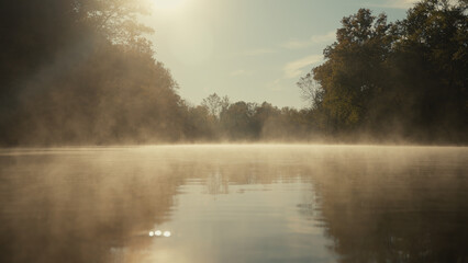 Fog drifting over a river during an autumn sunrise
