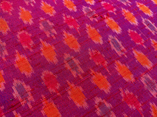 close-up of vibrant pink, orange, and purple Ikat fabric showcases the stunning interplay of colors and textures on pure raw silk.