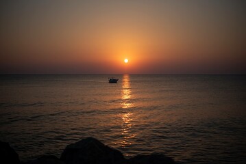 Obraz premium A stunning sunrise over the sea on the island of Crete, Greece. The calm waters reflect the golden hues of the morning sky, creating a peaceful seascape.