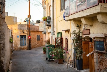 Fototapeta premium Narrow Greek streets in Hersonissos, Crete, Greece, lined with charming whitewashed buildings, colorful flowers, and vibrant local shops, exuding charm.