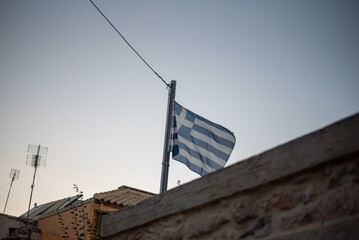 The Greek flag waves proudly in the breeze above rooftops in Hersonissos, Crete, Greece, set...